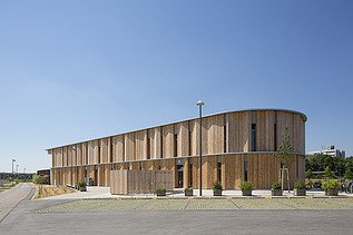 Außenaufnahme der Kindertagesstätte Campeon Infineon in Neubiberg. Man sieht ein Gebäude mit Holzfassade.