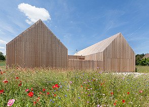 Foto eines modernen Holzhauses in U-Form mit Holzfassade. LENO-BSP.
