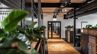 Photo of an interior of the Maisel brewery in Bayreuth. You can see a hallway with a wooden ceiling and floor.