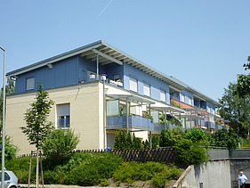 Foto eines mehrgeschossigen Gebäudes mit weiß-blauer Fassade.