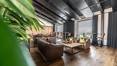 Photo of an interior of the Maisel brewery in Bayreuth. You can see a lounge with a wooden floor.