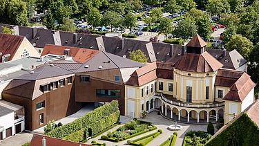 Luftaufnahme mehrerer Gebäude, auch von einer Kirche und Aufstockung aus LENO-Brettsperrholz.