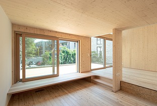 Foto eines Wohnhauses aus Holz. Unmöbliertes Wohnzimmer mit vielen Holzoberflächen.