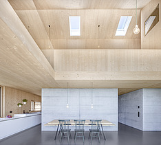 Foto eines modernen Holzhauses mit Holzfassade. Innenaufnahme Esszimmer. Holz- und Betonwände.