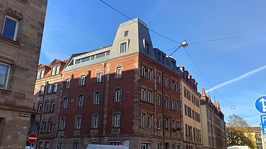 Photo of a wooden extension. You can see several tall buildings.