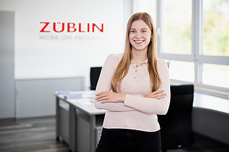 Photo of a young woman with folded arms. Training ZÜBLIN Timber.