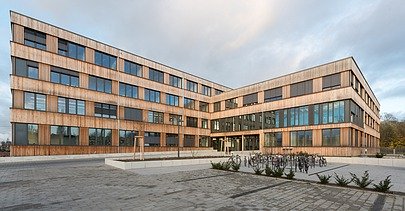Photo of the Flexim Berlin office building from the outside. You can see a large wooden building with a wooden façade and flat roof.