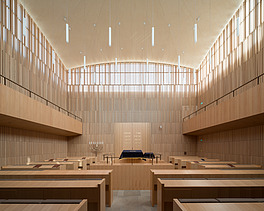 Photo of the interior of a synagogue. Wooden walls and ceilings and wooden benches can be seen