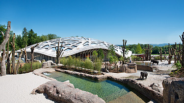 Foto des Elefantenparks in Zürich von außen. Zu sehen ist eine große Holzdachkonstruktion des Gebäudes.