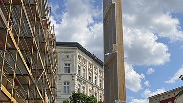 Foto der Holzbaumontage in der Stendaler Straße in Berlin. Man sieht ein großes LENO-ADD-Holzelement am Kran.