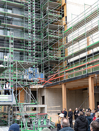 Foto eines Richtkranzes am neuen UmweltHaus in Nürnberg. Die Gäste lauschen dem Richtspruch.