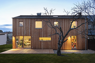 Photo of a modern wooden house. Dusk.