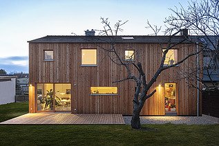 Photo of a modern wooden house. Dusk.