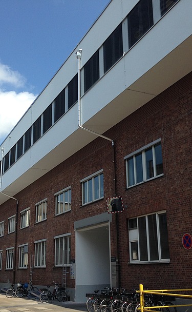 Foto eines mehrgeschossigen Gebäudes. Aufstockung aus Holz mit weißer Fassade und Flachdach.