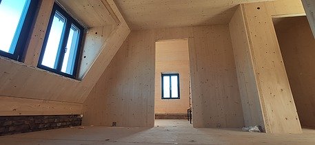 Photo of a building shell made of LENO cross laminated timber. You can see many wooden surfaces in one room