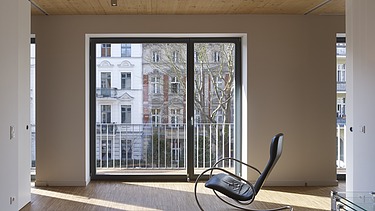 Foto eines Innenraumes mit Holzdecke. Es steht ein Schaukelstuhl darin.