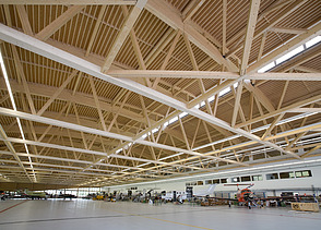 Foto der Montagehalle Pilatus CH-Stans. Zu sehen ist eine große Brettschichtholz-Dachkonstruktion.