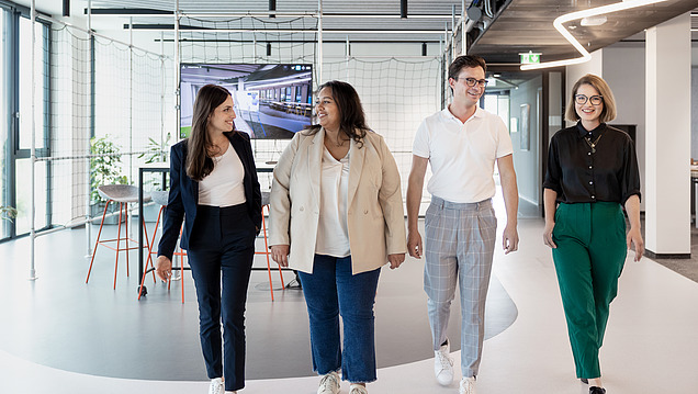 Photo of four young people walking in a row in a room.
