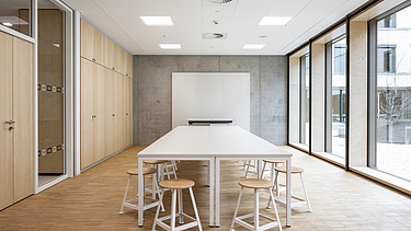 Interior photo of the Vinzenz Pallotti School in Friedberg. You can see a furnished meeting room and a timber mullion and transom façade.
