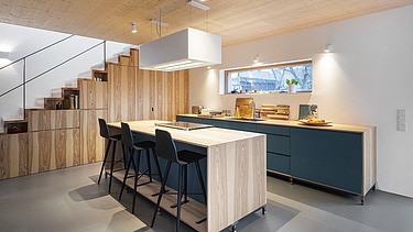 Foto eines Küchenwohnraumes mit sichtbarer LENO-Brettsperrholzdecke.