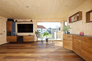 Foto eines Wohnhauses aus LENO-Brettsperrholz. Wohnzimmer mit vielen Holzoberflächen.