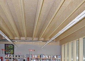 Photo of a library from the inside. The focus is mainly on the ribbed wooden ceiling.