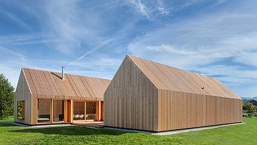 Foto eines modernen Holzhauses in U-Form mit Holzfassade. LENO-BSP.