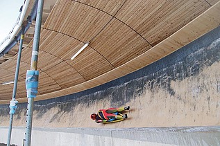 Foto einer Bobbahn mit Holzüberdachung und liegendem Bobfahrer