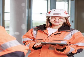 Photo of three people in orange work clothes on the building site.