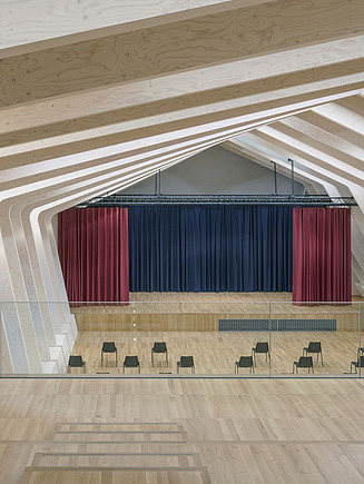 Photo of the Metropoliton School Berlin from the inside. You can see a stage and wooden surfaces built by ZÜBLIN Timber.