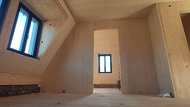 Foto eines Rohbaus aus LENO-Brettsperrholz. Man sieht viele Holzoberflächen in einem Raum