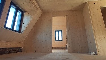 Photo of a building shell made of LENO cross laminated timber. You can see many wooden surfaces in one room