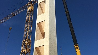 Foto eines Aufzugschachtes aus Holz während der Kranmontage.