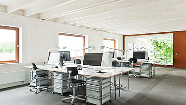 Photo of a furnished office space with visible, white ribbed wooden ceiling. Wooden extension.