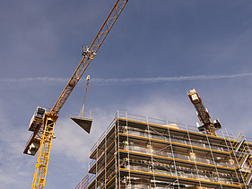 Foto des Rohbaus VINZENT in München. Zu sehen ist die Kranmontage eines Holzelements.