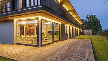 Foto der Anwaltskanzlei FGS Augsburg. Modernes Holzgebäude mit Flachdach und großzügiger Holzterrasse