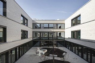 Außenaufnahme der Vinzenz-Pallotti-Schule in Friedberg. Man sieht ein großes, weißes Gebäude mit Flachdach und einem umliegenden Innenhof.