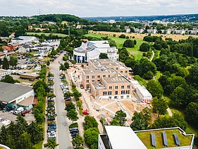 Foto der Uni Witten von außen. Man sieht ein großes Gebäudes aus Holz aus der Vogelperspektive.