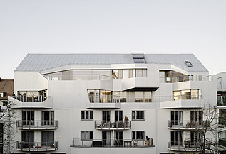 Foto eines mehrgeschossigen Gebäudes mit weißer Fassade. Aufstockung mit LENO-Brettsperrholz.