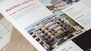 Foto der Innenseite der Image-Broschüre von ZÜBLIN Timber. Man sieht mehrere Gebäude aus Holz und die Überschrift Holzbau und Fassade.