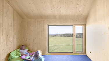 Foto eines modernen Holzhauses mit Holzfassade. Innenaufnahme Kinderzimmer. Sichtbare LENO-Holzwände.