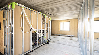 Photo of a building shell. You can see wooden walls and a bathroom module