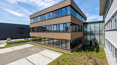 Foto eines Holzgebäudes mit Holz-Glasfassade und Flachdach.