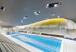 Foto des Aquatics Centres in London von innen. Zu sehen ist die Holzdachkonstruktion und ein großes Schwimmbecken.