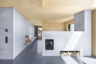 Foto eines modernen Holzhauses mit Holzfassade. Innenaufnahme Kaminzimmer. Holz- und Betonwände.