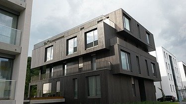 Foto eines mehrgeschossigen Wohngebäudes mit Holzfassade.