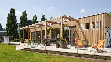 Photo of a wooden building with flat roof and terrace.