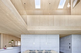 Sustainability at ZÜBLIN Timber Photo of a modern living room with an open wooden roof truss.
