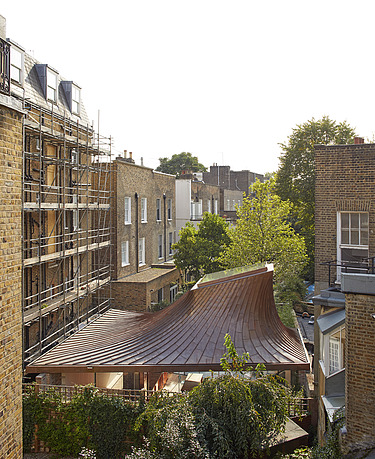Photo of a small building with a domed roof and surrounded by multi-storey buildings