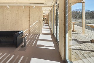 Foto eines Innenraums mit vielen Holzoberflächen und Glasfront.